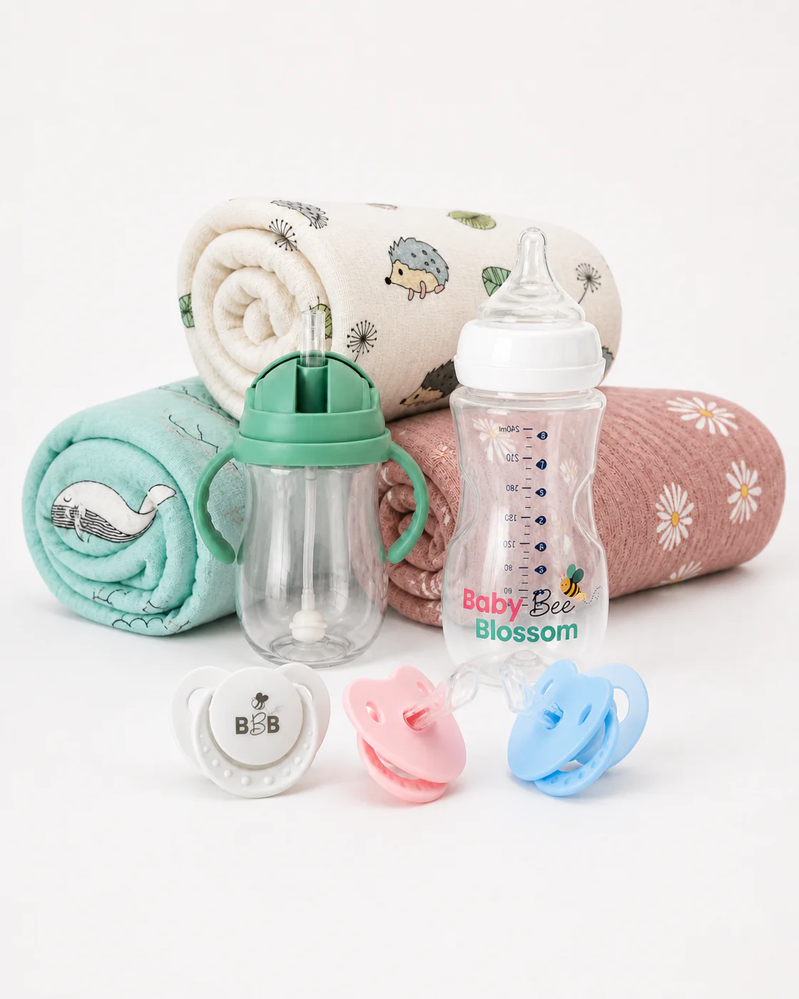 Baby Bee Blossom feeding bottles, sippy cup, muslin swaddles and pacifiers arranged together